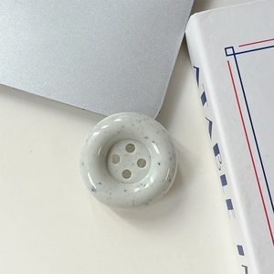 Détail du support de téléphone en forme de bouton crème avec taches noires