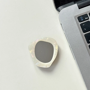 Detail of artistic iridescent shell phone grip with grey inlay against office laptop