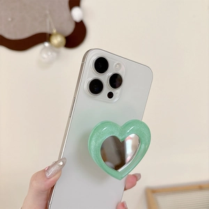 Light green heart-shaped phone grip with built-in mirror on a white smartphone