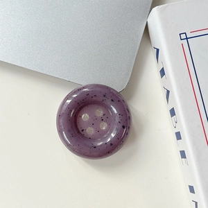 Vue de dessus d'un support de téléphone en bouton violet avec des taches noires mouchetées