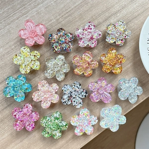 Set of 15 colorful glitter 3D flower phone sockets on a light wood background