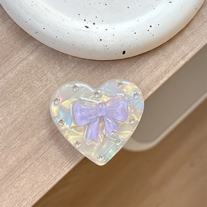 Macro shot of heart-shaped magnetic phone grip with purple bow and rhinestones