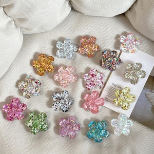 Glitter sequins 3D flower phone socket grips in various colors on a textured cloth