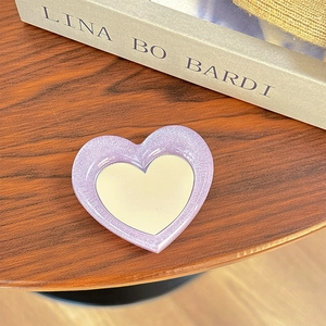 Close-up of heart-shaped glitter phone socket with a mirror on a rustic wooden desk