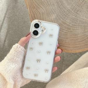 Close-up of white iPhone case with silver bows and pearl charms on a soft rustic background