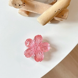 Close-up of a pink cherry blossom phone grip with glitter sequins on a white surface
