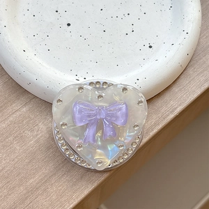 Macro detail of heart-shaped phone grip with purple bow and sparkling rhinestones