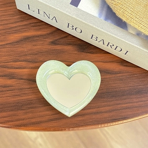 Macro shot of heart-shaped glitter phone socket with a mirror center on a wood table