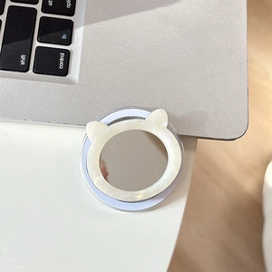 Detail of round cat-ear phone socket with built-in makeup mirror on a white desk