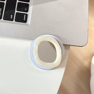 Detailed view of a pearl resin phone grip mirror placed on a silver laptop keyboard