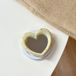 Detail of cream heart MagSafe phone grip with mirror surface and black ink splatters
