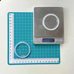 Detail view of a 6cm light blue glitter phone grip base weighing 13.4g on a scale