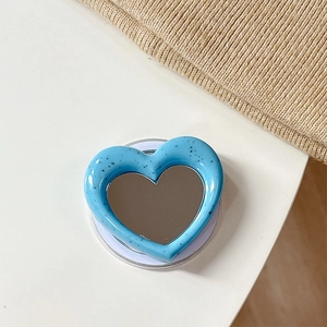 Close-up of blue heart-shaped MagSafe phone grip with splattered texture and makeup mirror