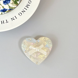 Détail du support de téléphone coeur avec texture perle, nœud et strass scintillants