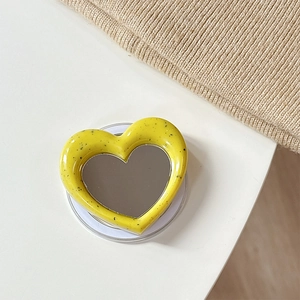 Macro shot of heart-shaped magnetic phone grip with yellow splatter pattern and mirror