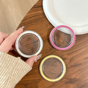 Close-up of three glittered phone lens rings in pink, yellow, and sparkling white colors