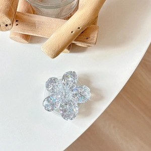 Detail of flower-shaped phone grip with glitter and sequins on a minimal desk setup
