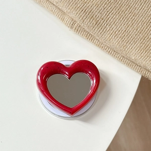 Detail view of red heart-shaped MagSafe phone grip with built-in makeup mirror and dots
