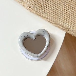 Detail of heart-shaped magnetic phone grip featuring grey terrazzo texture and mini mirror