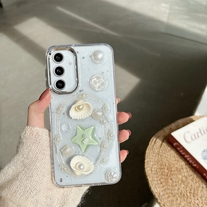 Detail of clear phone case with 3D ocean charms, pearls and glitter accents held by hand