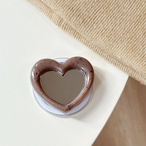 Macro shot of heart-shaped magnetic phone grip with brown marble texture and makeup mirror
