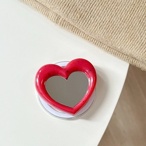 Detail of red heart-shaped MagSafe phone grip with black polka dots and a built-in mirror