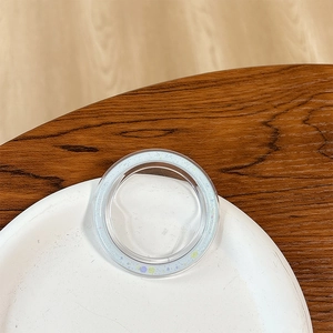 Close-up of a round mobile phone grip with pastel star patterns on a wooden surface