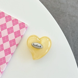 Detail of yellow heart phone grip with pearlescent finish and handmade silver label