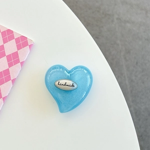 Detail of blue heart-shaped phone grip with a handmade silver metal tag and pearl finish