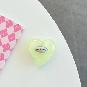 Detail of light green heart phone socket with handmade silver tag and pearlescent resin