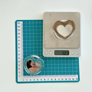 Close-up of glitter heart phone grip and makeup mirror on scale showing 30.3g weight