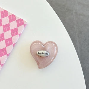 Detail of pink glitter heart phone grip featuring a handmade silver metal tag