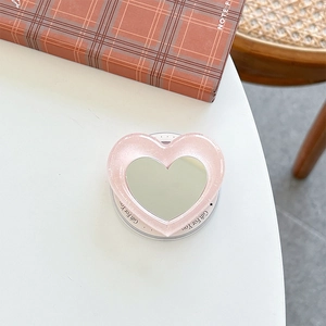 Macro shot of pink glitter heart phone grip with mirror on a cozy desk background