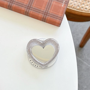 Macro shot of glittery heart phone grip mirror with Gift for You text base on a table
