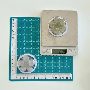 Detail view of 3D glitter flower phone stand showing weight of 29.9g on a scale