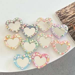 Glitter heart-shaped phone socket mirrors with colorful mini fruit slices set on white