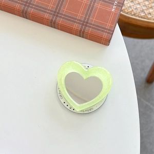 Close-up of glitter heart makeup mirror phone grip with Gift For You card on desk