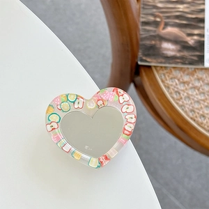 Close-up of heart-shaped glitter phone grip with colorful fruit resin slices pattern