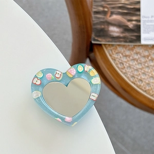 Detail of blue glitter heart phone socket with colorful fruit patterns on white table