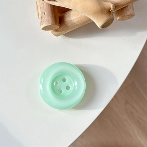 Detailed top view of a translucent mint green round four-hole button phone socket grip