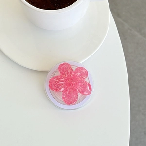 Close-up of pink cherry blossom phone grip with gold glitter on white background