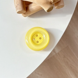 Close-up of a bright yellow resin button phone grip on a clean minimalist desk