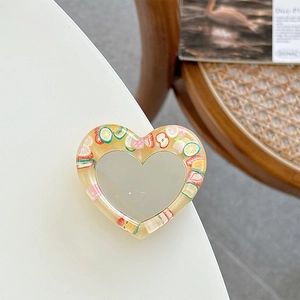 Detail of heart-shaped glitter phone grip with resin fruit slices and mirror center