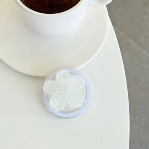 Close-up of glittery white flower phone grip stand on a minimalist white table surface