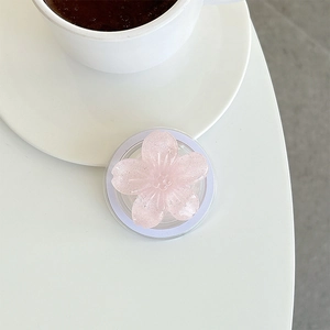 Detail of pink glitter sakura flower phone grip with magnetic base on white desk