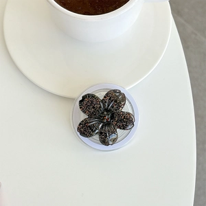 Close-up of a 3D glittery cherry blossom phone grip on a minimalist white desk surface