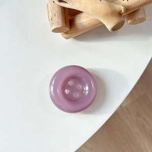 Detail of purple resin button phone grip with classic four-hole design and glossy finish