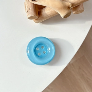 Detail of a sky blue round button phone socket on a minimalist white background