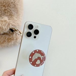 Sparkly rhinestone phone grip with silver dolphin and heart mirror on white background