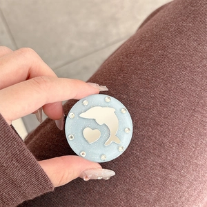 Close-up of a blue dolphin and heart glitter phone grip held in a person's hand